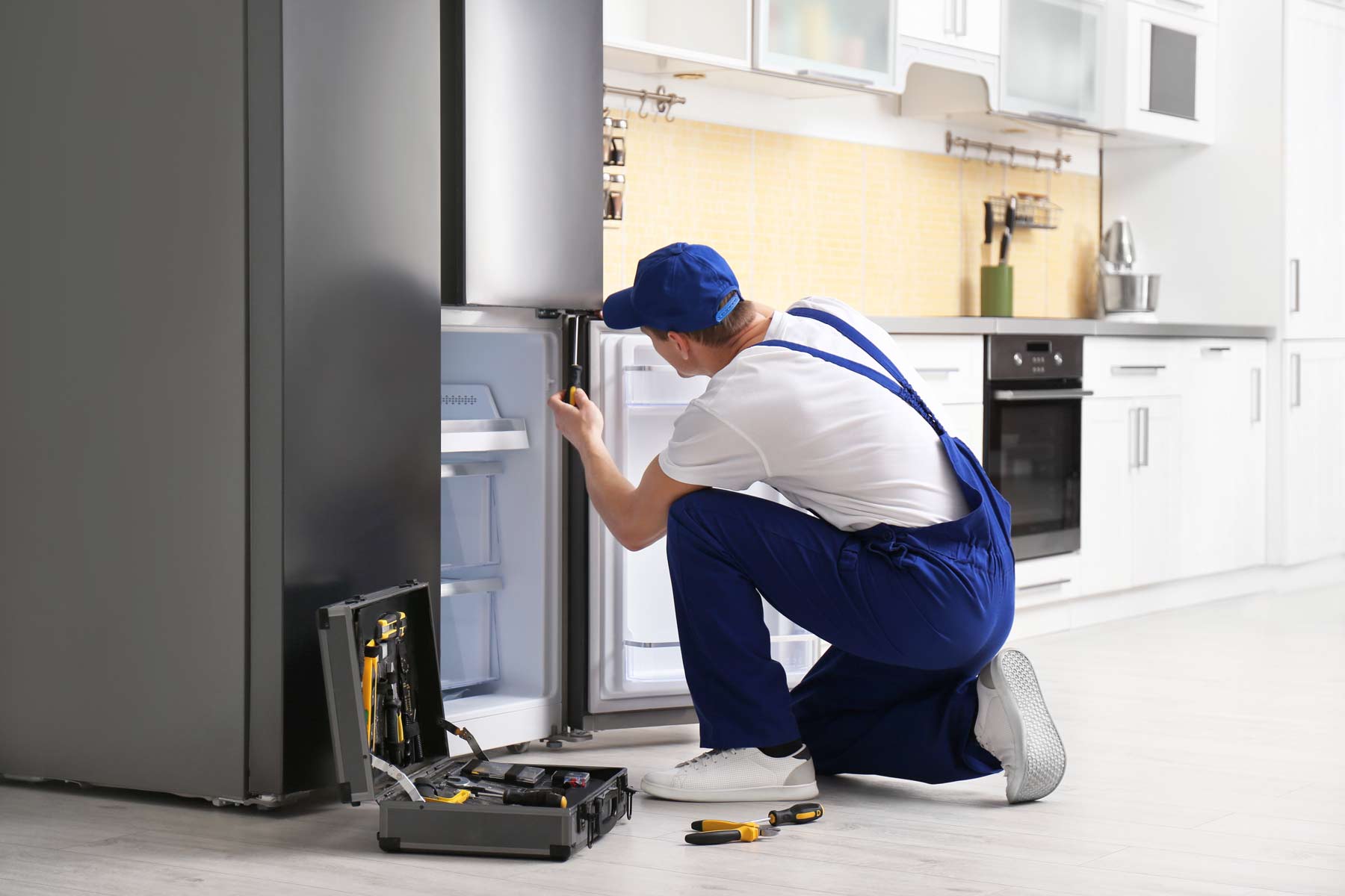 homeguide-repair-technician-fixing-a-refrigerator-and-freezer